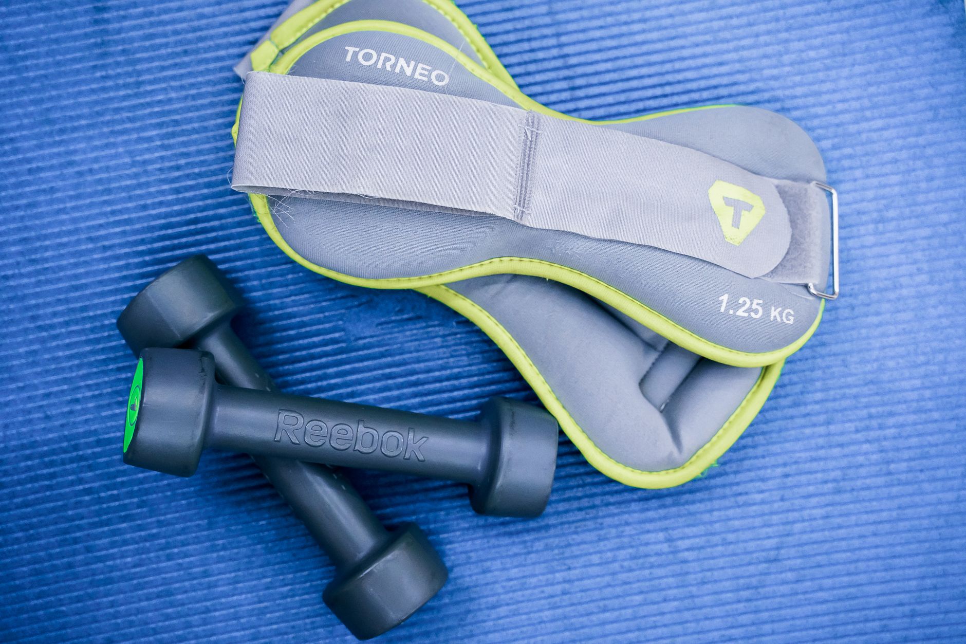 From above of modern dumbbells and leg weight belts placed on blue fitness mat in studio — How Can I Maximize 2 Hours Per Wee
